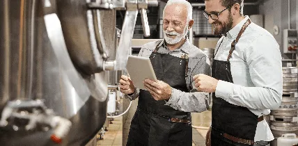Dois profissionais analisando dados em um tablet dentro de uma cervejaria